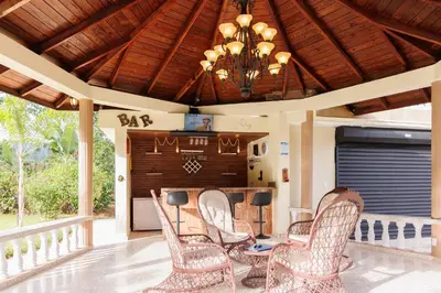 a porch with chairs and a table and a chandelier at Rancho Don Pedro in Bonao