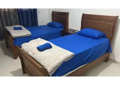 two beds in a room with blue and white sheets at Tu guarida in Santo Domingo