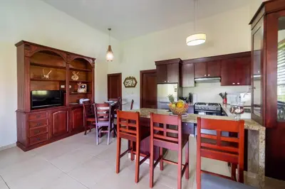 a kitchen with wooden cabinets and a table with chairs at Reina del Mar 5 in Cafemba