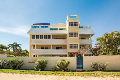 a tall white building with a fence in front of it at Reina del Mar 5 in Cafemba