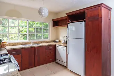 a kitchen with wooden cabinets and a white refrigerator at Reina del Mar 5 in Cafemba