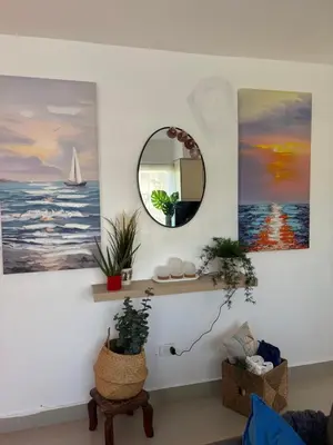 a living room with paintings on the wall and a mirror at Albatros Cozy Apt in Juan Dolio