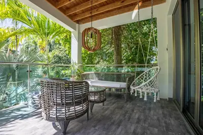 a porch with wicker chairs and a swing at ProCab Kaya Apartments Cabarete in Cabarete