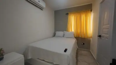 a white bed in a room with a window at Aparta Hotel Ana Julia in Sosúa