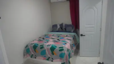 a small bedroom with a bed with a colorful comforter at Aparta Hotel Ana Julia in Sosúa