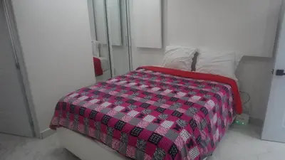 a bedroom with a bed with a pink and black comforter at Aparta Hotel Ana Julia in Sosúa
