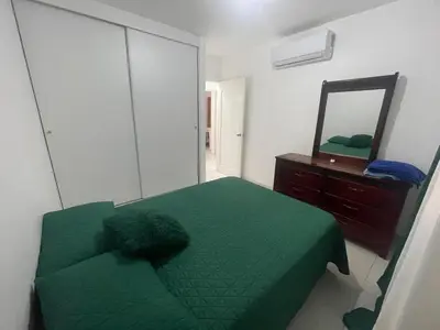 a bedroom with a green bed and a mirror at Apartamento en Edificio Palmares in La Romana