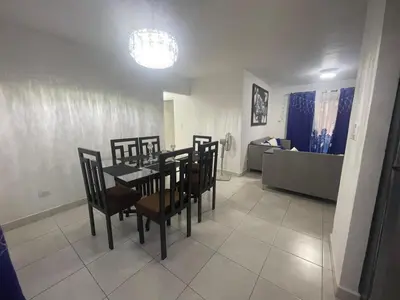 a dining room with a table and chairs and a living room at Apartamento en Edificio Palmares in La Romana