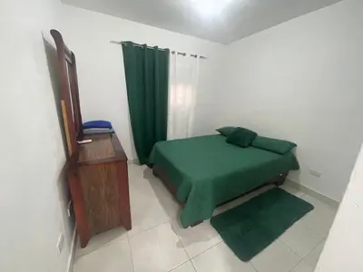 a bedroom with a green bed and a green curtain at Apartamento en Edificio Palmares in La Romana