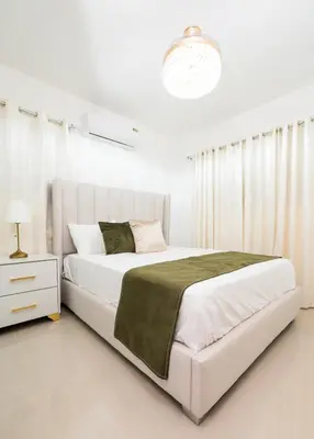 a white bedroom with a large bed and a lamp at Blue Lux in Santiago de los Caballeros