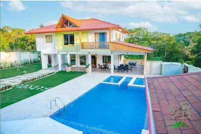 a house with a swimming pool in front of a house at Villa del Bosque, Vacacional Matua in La Piña