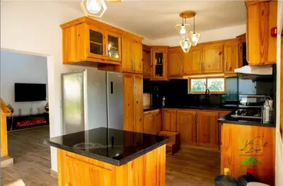 a kitchen with wooden cabinets and a black counter top at Villa del Bosque, Vacacional Matua in La Piña