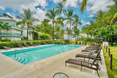 a swimming pool with lounge chairs and palm trees at Oceanfront Apt W- Private Beach - Las Terrenas in El Limón