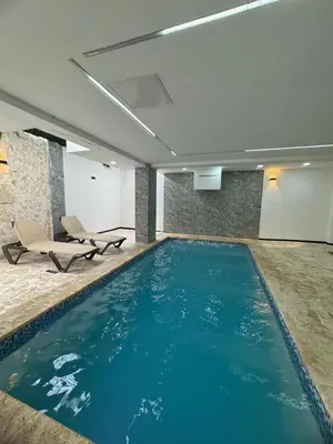 a large swimming pool in a building with a chair at Apartamento Santo Domingo este in Juan López