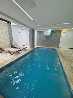 a swimming pool in a room with chairs and blue water at Apartamento Santo Domingo este in Juan López