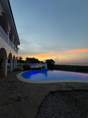 a swimming pool in front of a building with a sunset at Desconéctate de la civilización in Nagua