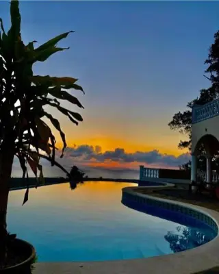 a swimming pool with a sunset in the background at Desconéctate de la civilización in Nagua