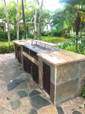 a large stone island in a patio with palm trees at Infiniti blu beautiful apartment at the pool in Sosúa