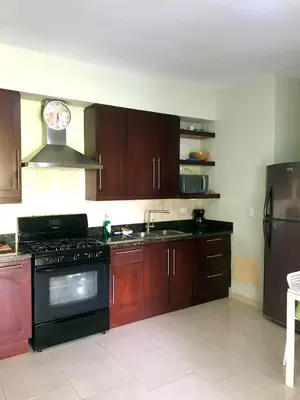 a kitchen with wooden cabinets and a black stove at Infiniti blu beautiful apartment at the pool in Sosúa