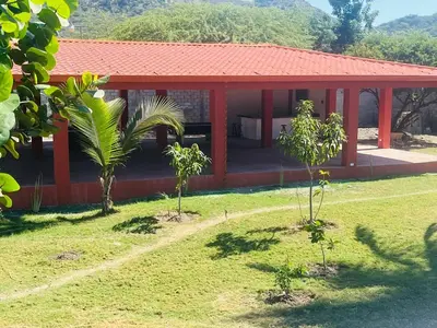 a house with a red roof with trees in front of it at Villa Rosa Bella Perfect for families or groups in Palmar de Ocoa