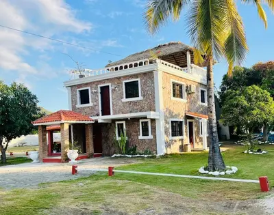 an old house with a palm tree in front of it at Villa Rosa Bella Perfect for families or groups in Palmar de Ocoa
