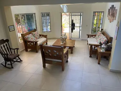 a living room with chairs and tables and windows at La Cigua in Pedro Brand