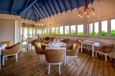 a restaurant with white tables and chairs and windows at Viva V Samana by Wyndham, A Trademark Adults All Inclusive in Las Terrenas