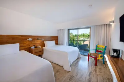 a hotel room with two beds and a chair at Viva V Samana by Wyndham, A Trademark Adults All Inclusive in Las Terrenas