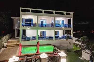 a large house with a swimming pool in front of it at Beautiful ocean and mountain view villa in Gaspar Hernández