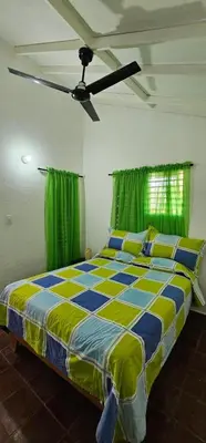 a bedroom with a large bed with green curtains at Villa Jardín Tropical in Las Galeras