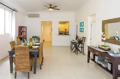 a dining room and living room with a table and chairs at Club Hemingway Amplio Apartamento en la Playa de Juan Dolio in Los Corrales