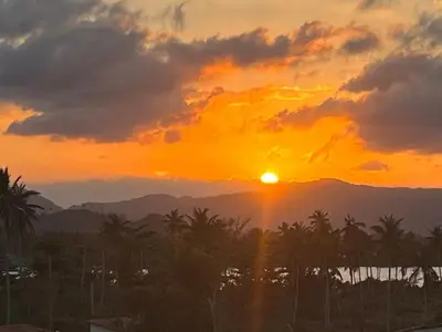 a sunset over the mountains and palm trees at Gecko Azul, Las Galeras in Las Galeras