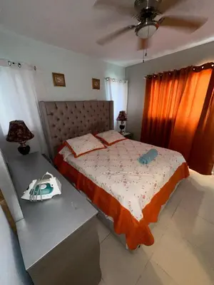a bedroom with a bed and a table with a purse at La Romana Caleta Apartment in La Romana