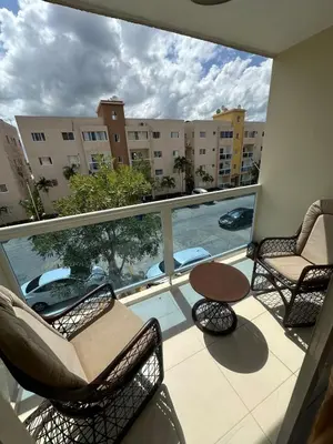 a balcony with chairs and a table and a large window at La Romana Caleta Apartment in La Romana