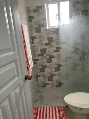 a bathroom with a toilet and a glass shower at Apartamento acogedor a 5 minutos de la playa in San Felipe de Puerto Plata