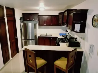 a kitchen with wooden cabinets and a counter top at Cozy, comfortable three-bedroom condo in Santiago,DR in Santiago de los Caballeros