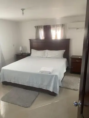 a bedroom with a large bed with white sheets and pillows at Cozy, comfortable three-bedroom condo in Santiago,DR in Santiago de los Caballeros