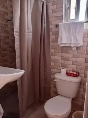 a bathroom with a white toilet and a sink at Dona Beba Guesthouse in La Caleta
