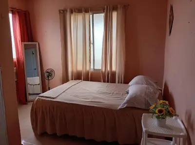 a bedroom with a bed with a window and flowers on a table at Dona Beba Guesthouse in La Caleta
