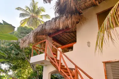 a staircase leading up to a thatched house with palm trees at Paradiso del Caribe Apartments A1 and A2, Your Perfect Stay in Las Galeras in Las Galeras