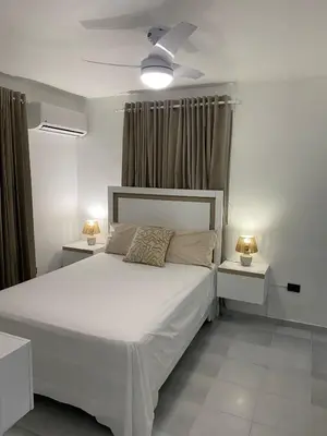 a bedroom with a white bed with two night stands at Apartamento en el Batey de Sosua in Sosúa