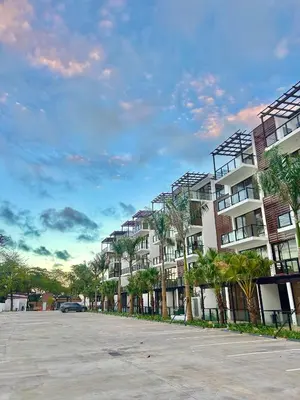 a row of apartment buildings with palm trees in a parking lot at GH Condos by Sunrise3 in Puerto Plata