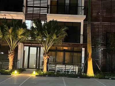 a building with palm trees and a bench in front of it at GH Condos by Sunrise1 in San Felipe de Puerto Plata