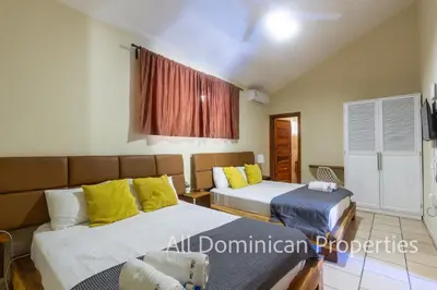 two beds with yellow and blue pillows in a room at Sosua Private villa, 9 br, guest friendly, Up to 20 persons! in Sosúa