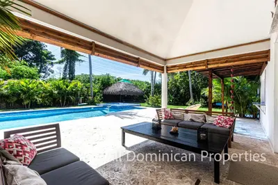 a living room with a table and a swimming pool at Sosua Private villa, 9 br, guest friendly, Up to 20 persons! in Sosúa