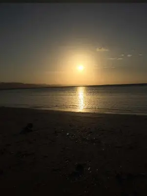 a sunset on the beach with the sun setting at Santa's Villa Punta Rucia in Punta Rucia