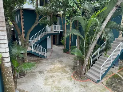 a blue building with stairs and palm trees at Solano Apartamentos in Boca Chica