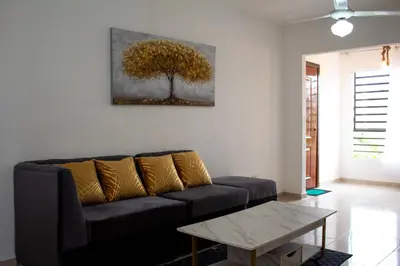 a living room with a couch and a tree painting on the wall at Apartamento tranquilo y cómodo in La Javilla