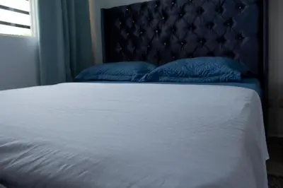 a bed with a blue headboard and two blue pillows at Apartamento tranquilo y cómodo in La Javilla