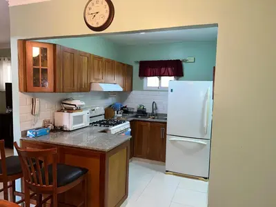 a kitchen with a white refrigerator and a clock on the wall at Tranquilo Apartamento de 3 habitaciones in Los Paredones